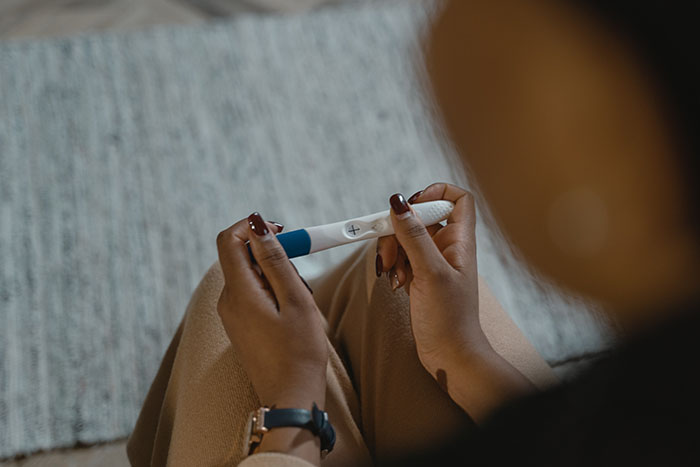 woman looking at positive pregnancy test